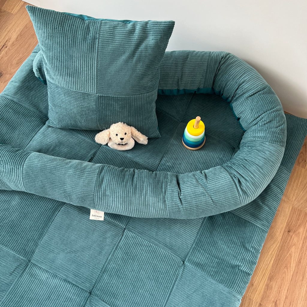 A cozy blue pet bed with a stuffed animal dog and a colorful stacking toy on a wooden floor.